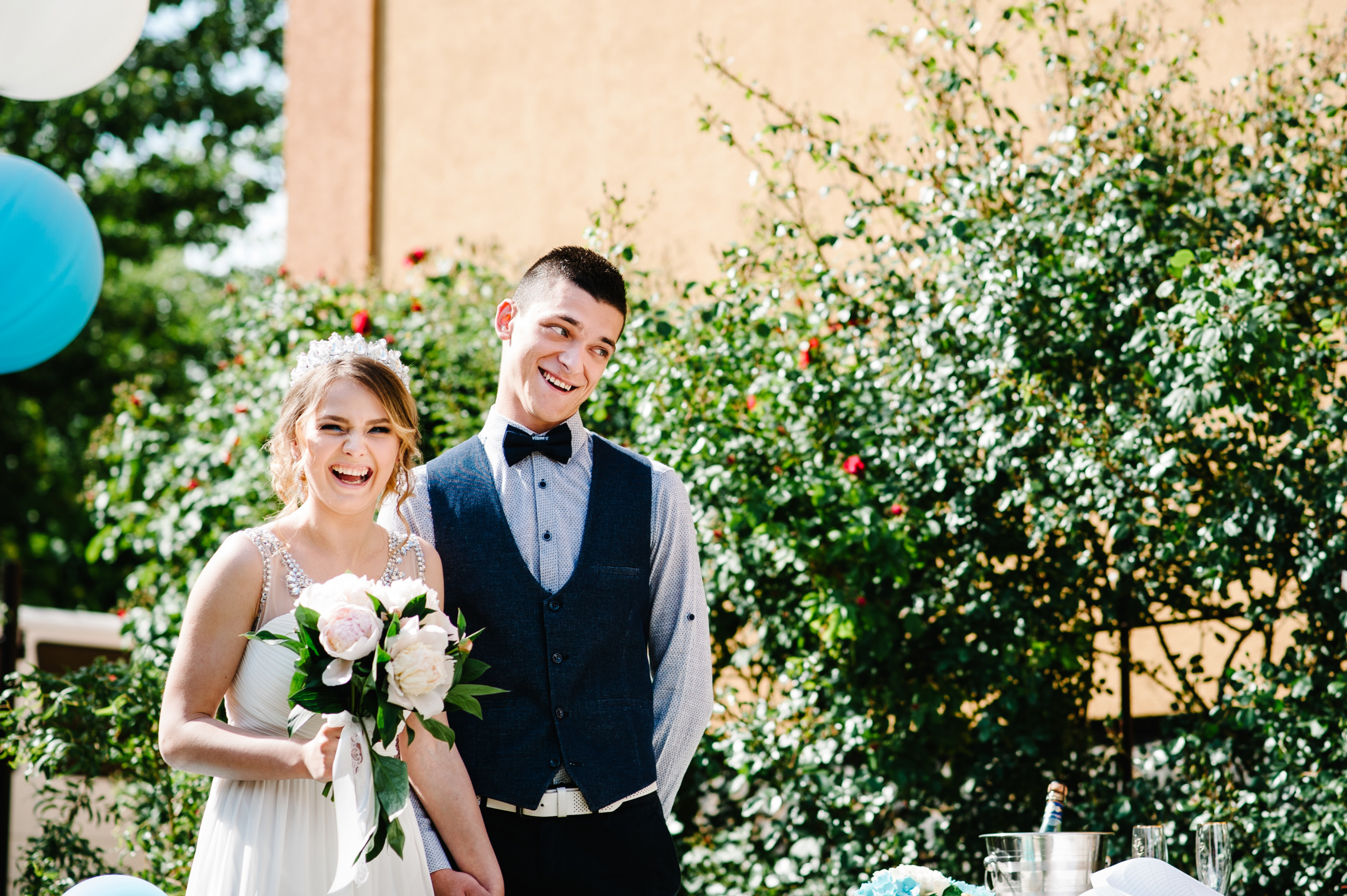 Stylish happy bride with a bouquet of peonies and groom hold hands. On the background of balloons on the nature in the courtyard of the house. Waiting for the ceremony. Wedding Morning. Close up.